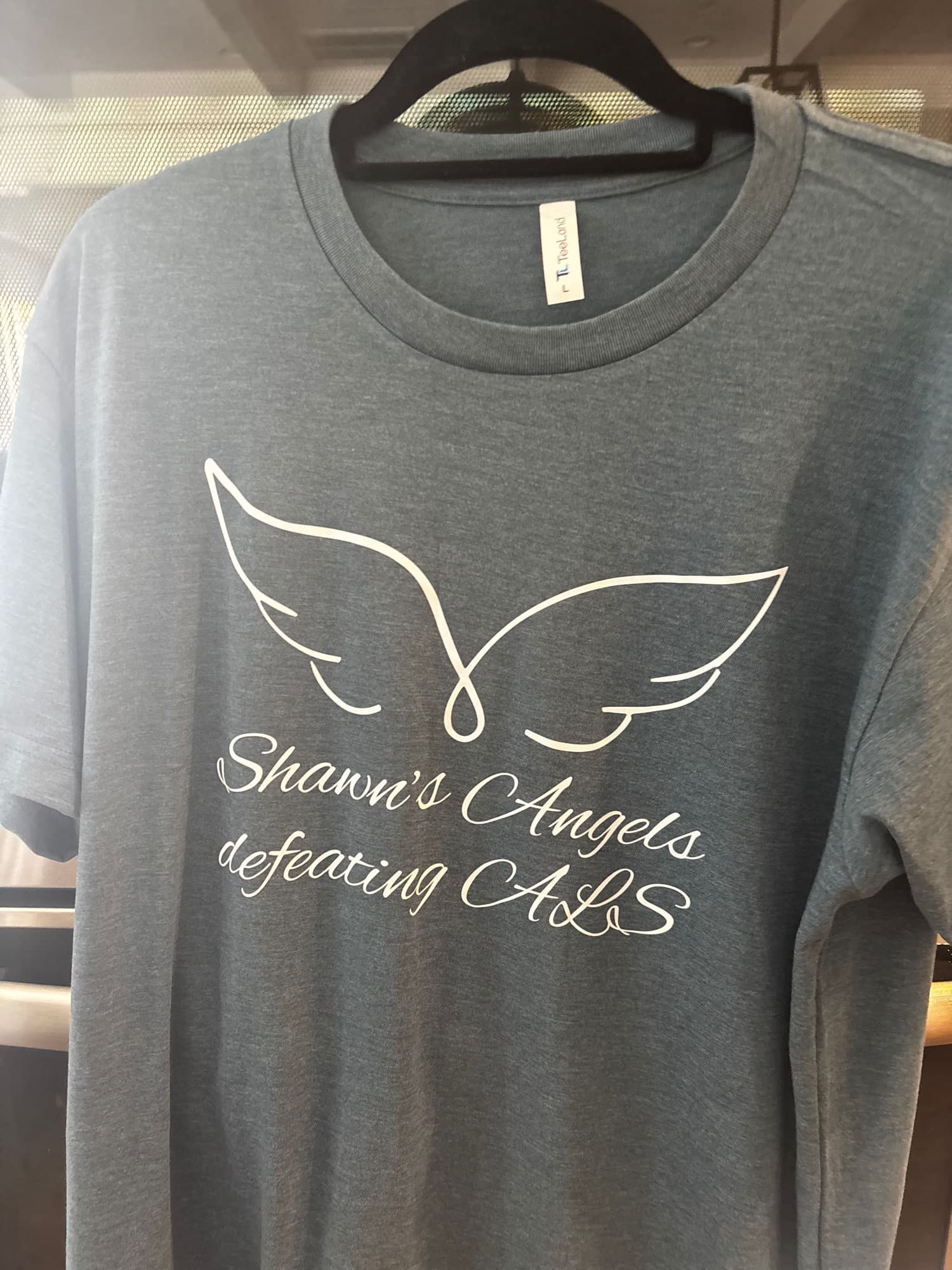 The Shawn’s Angels t-shirt: angel wings over the words Shawn’s Angels defeating ALS